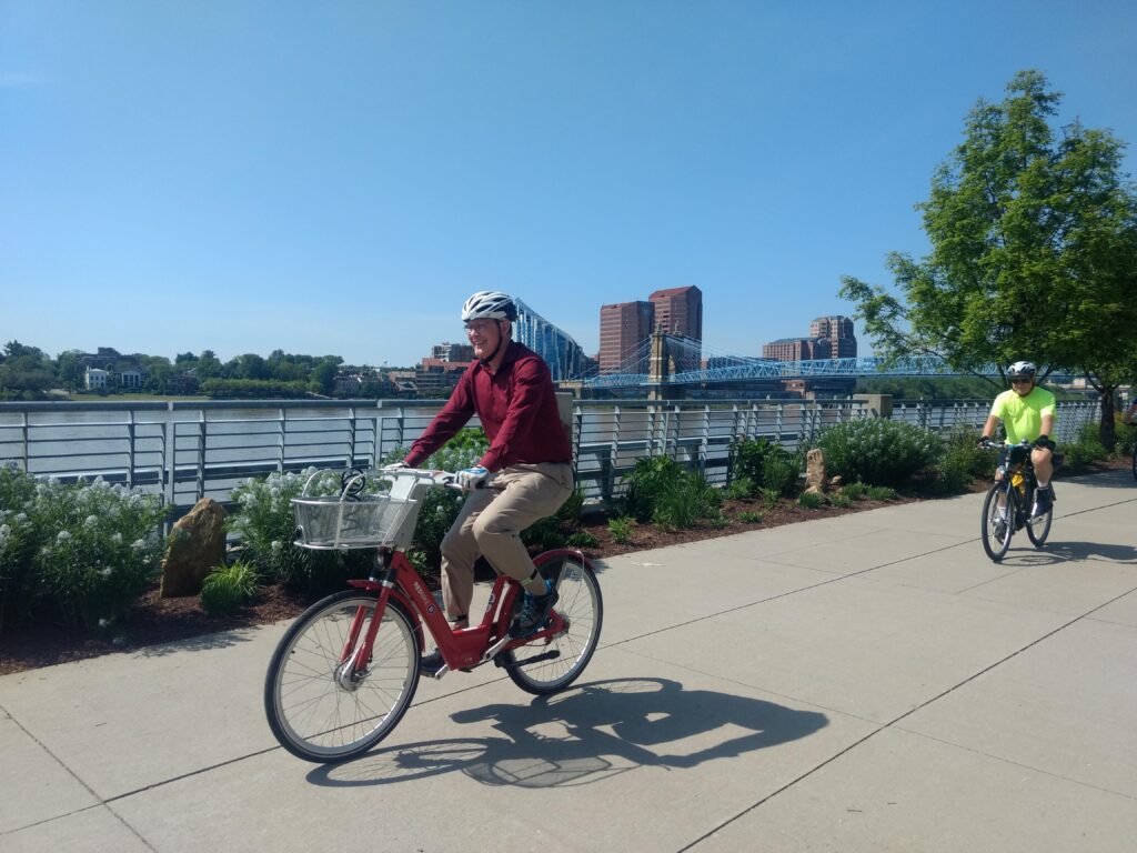 two men riding bicycles next to Ohio River in downtown Cincinnati